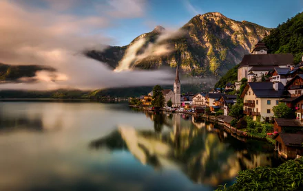 Scenic 8K Ultra HD view of Hallstatt, Austria, featuring man-made houses reflected in a tranquil lake against a backdrop of misty mountains.