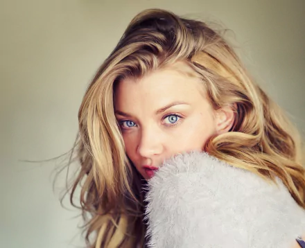 Close-up HD portrait of English actress Natalie Dormer with blonde hair and striking blue eyes, set against a soft, neutral background.