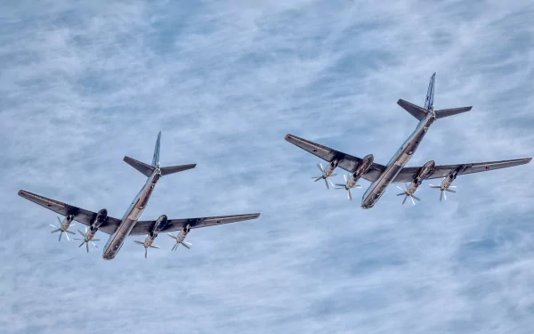 Two Tupolev Tu-95 military bombers fly in formation against a cloudy sky, showcasing powerful propeller-driven air force warplanes.
