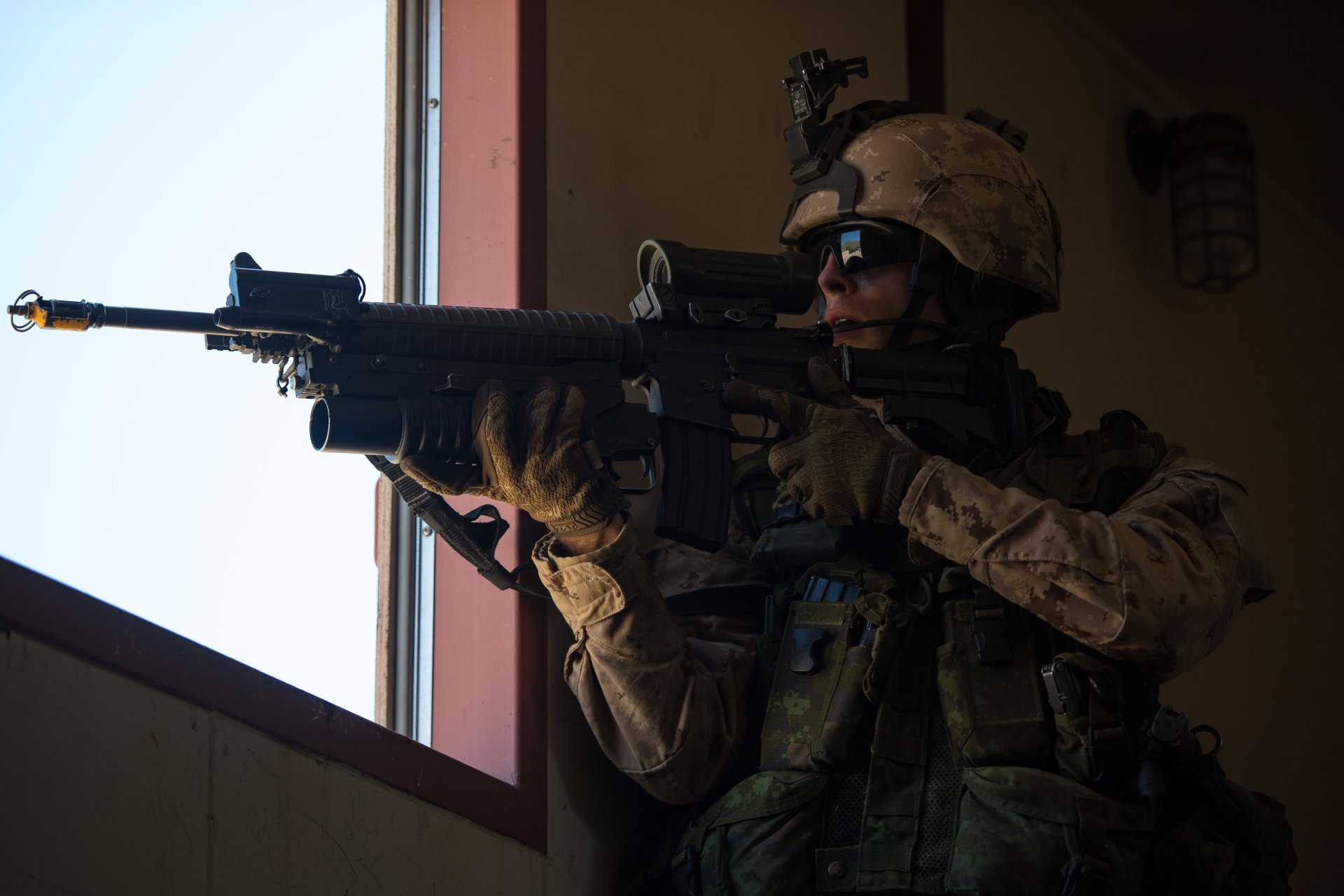 Military soldier aims an assault rifle indoors, captured in a detailed 4K Ultra HD PC desktop wallpaper and background.