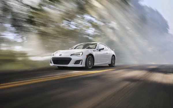 A sleek white Subaru BRZ speeds along a tree-lined road, capturing the essence of dynamic motion in this HD desktop wallpaper.
