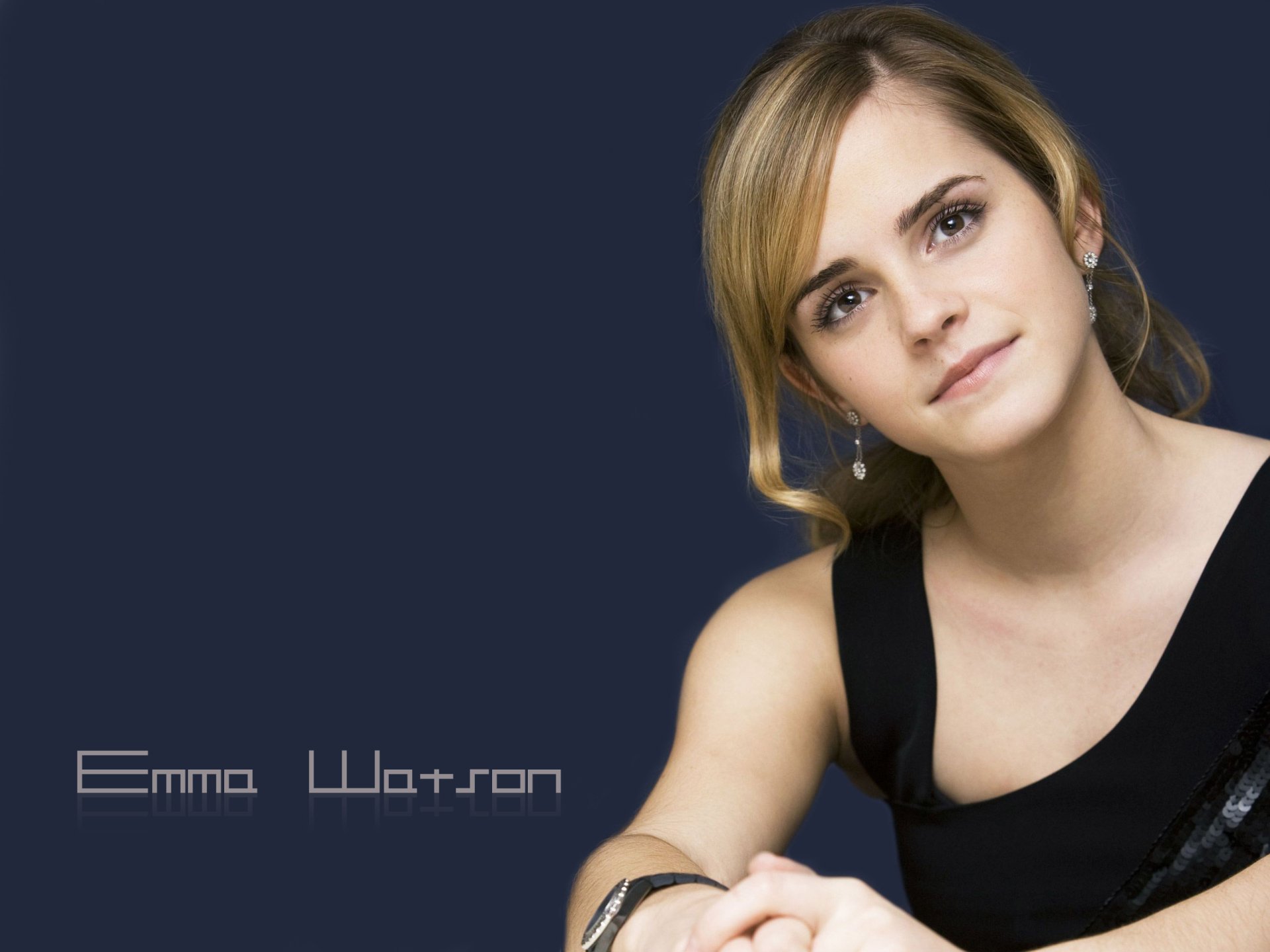A stunning HD desktop wallpaper featuring Emma Watson, showcasing her elegant pose and captivating expression against a minimalist dark background.