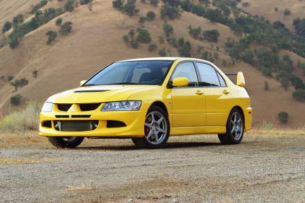 A vibrant yellow Mitsubishi Lancer Evolution parked on a gravel surface, with a picturesque backdrop of rolling hills, showcasing its sleek design and sporty aesthetics.