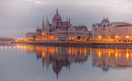 HD wallpaper showcasing the Hungarian Parliament Building along the Danube River in Budapest, with its illuminated architecture beautifully reflected in the water.