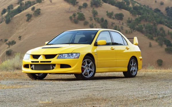 A vibrant yellow Mitsubishi Lancer Evolution parked on a gravel surface, with a picturesque backdrop of rolling hills, showcasing its sleek design and sporty aesthetics.