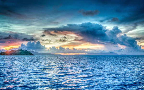 A stunning view of the ocean at Bora Bora, showcasing vibrant clouds and a colorful horizon under a dramatic sky. This 4K Ultra HD wallpaper captures the beauty of nature.