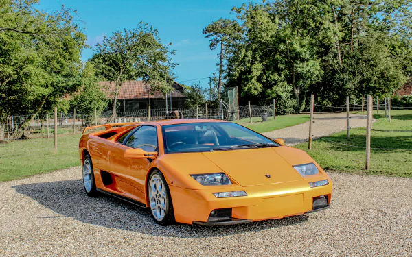 Orange Lamborghini Diablo supercar parked on a gravel driveway with trees and lawn — 4K Ultra HD PC desktop wallpaper.