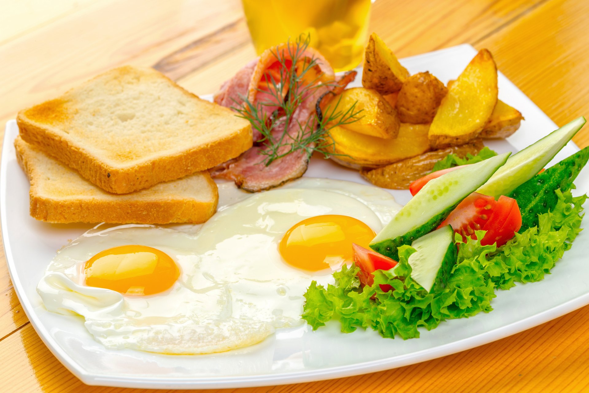 A vibrant 4K Ultra HD desktop wallpaper featuring a meal with two sunny-side-up eggs, toasted bread, potato wedges, fresh salad, and slices of ham on a white plate.