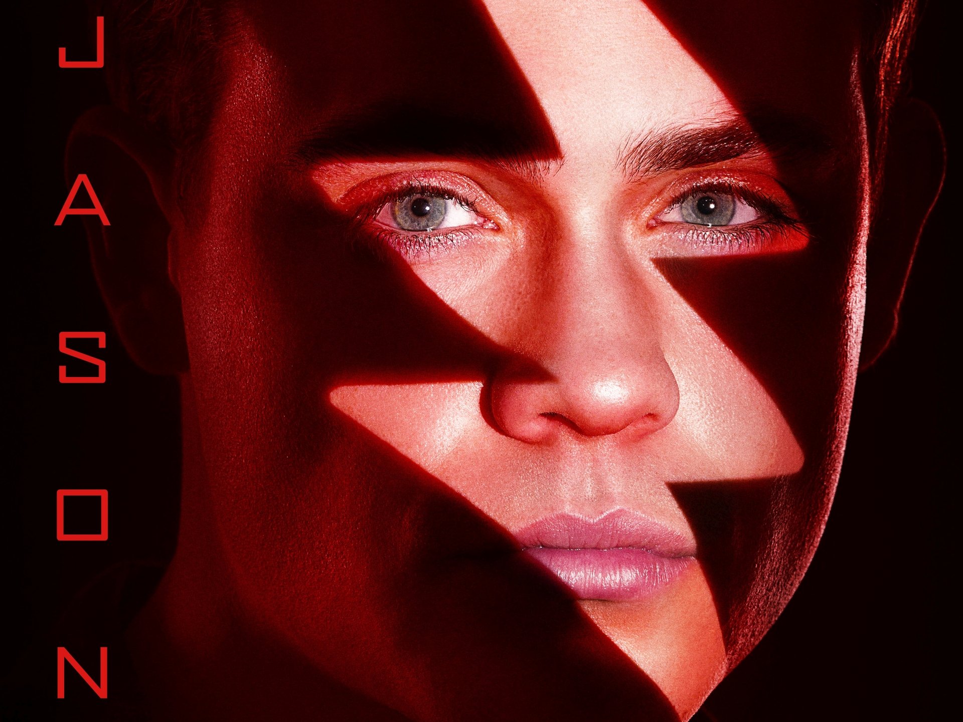 Close-up portrait from the Power Rangers (2017) movie: face lit in red with lightning-bolt shadows and piercing blue eyes — 2K Quad HD PC desktop wallpaper and background.