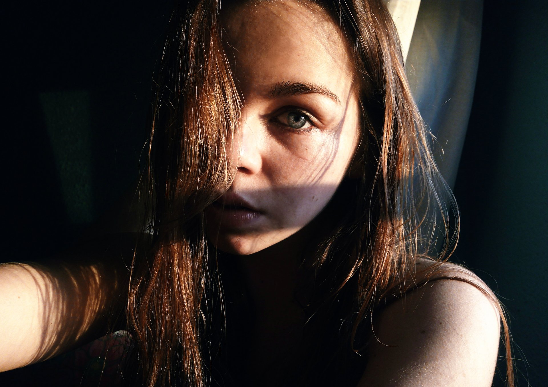 Close-up of a brunette woman with striking blue eyes, softly illuminated by natural light, captured in sharp 4K Ultra HD detail.