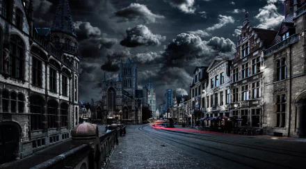 A dramatic night scene in Ghent, Belgium, featuring striking architecture and a cathedral under a cloudy sky. Light trails from passing vehicles add dynamic energy to the dark cityscape.