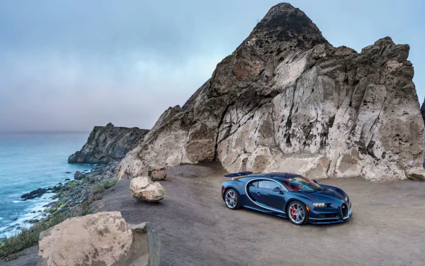 A stunning Bugatti Chiron parked near a rocky cliff, overlooking a serene ocean. This 4K Ultra HD wallpaper captures the beauty of both the supercar and its breathtaking surroundings.