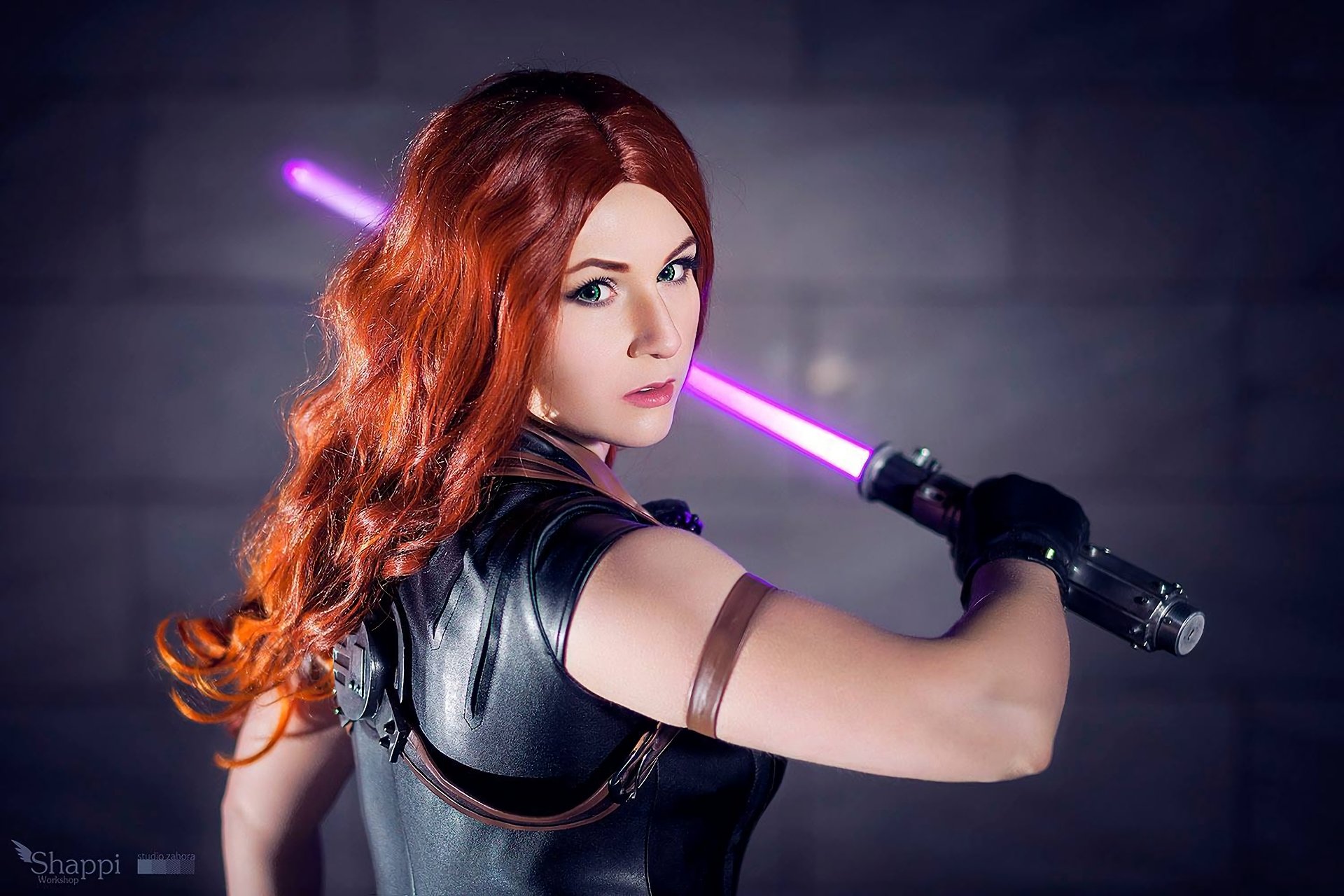 A woman in Star Wars cosplay, wielding a purple lightsaber and dressed in a black leather outfit, poses confidently. This HD desktop wallpaper captures the essence of a galaxy far, far away.