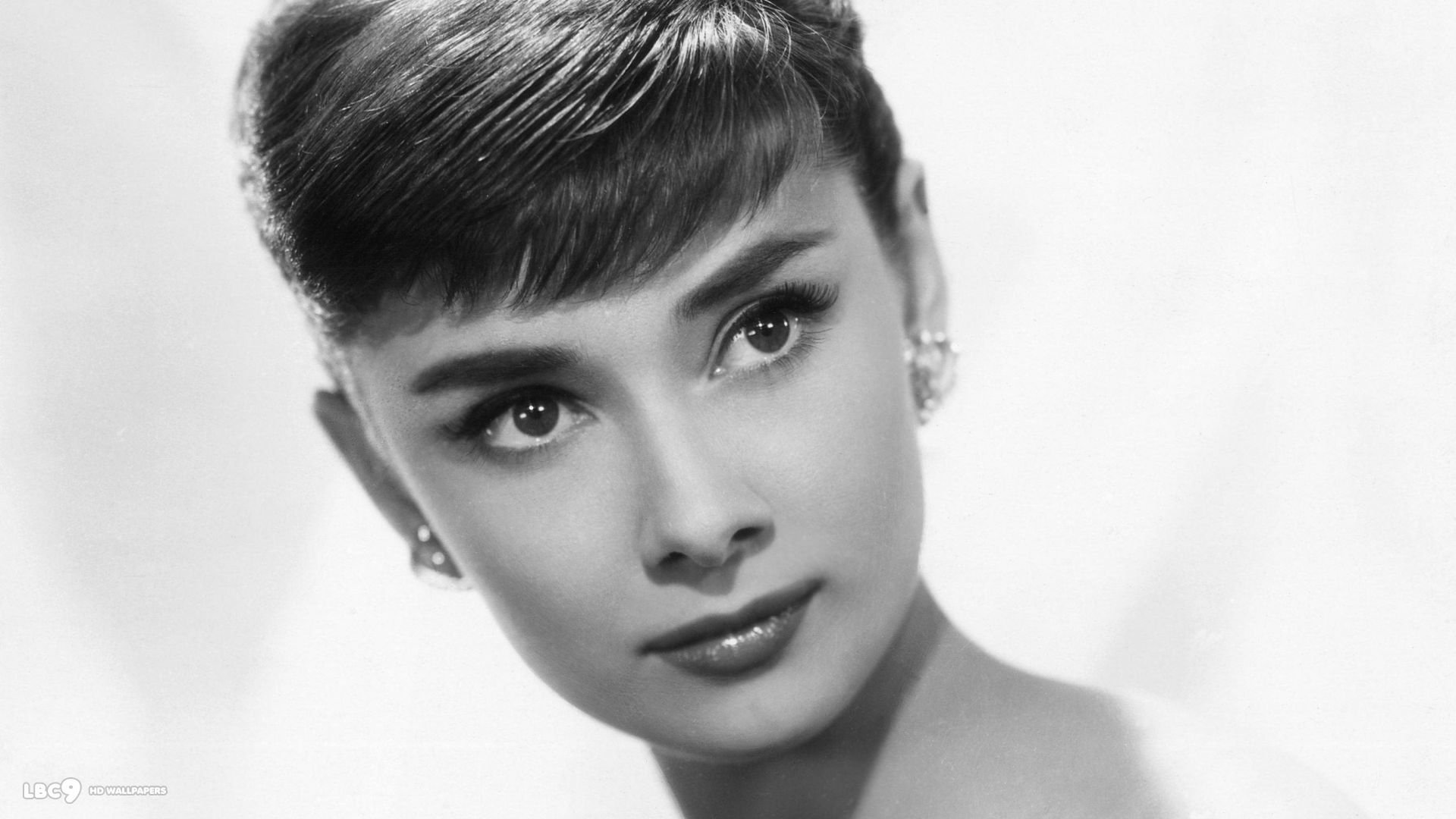 Black and white HD desktop wallpaper featuring a close-up portrait of celebrity Audrey Hepburn with elegant makeup and hairstyle.