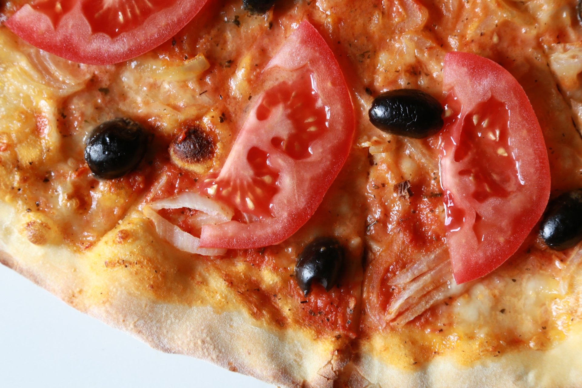 Close-up of a pizza topped with melted cheese, sliced tomatoes, and black olives, presented as a 4K Ultra HD PC desktop wallpaper.