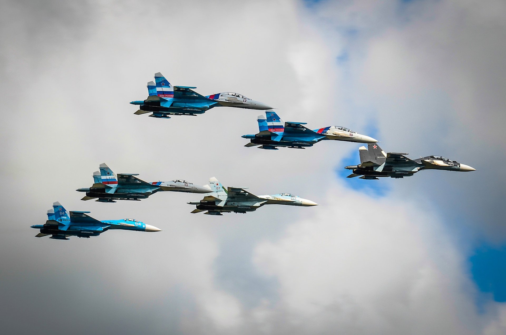Formation of six Sukhoi Su-27 jet fighter warplanes flying against a cloudy sky, captured in high-definition for a military aircraft desktop wallpaper.