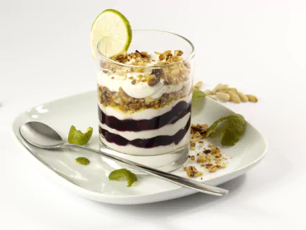 HD desktop wallpaper featuring a layered yogurt dessert with granola, fruit compote, lime garnish, and a spoon on a white plate.