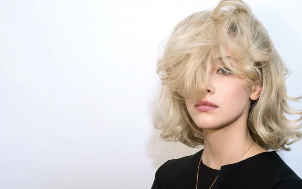 Close-up portrait of Canadian actress Sarah Gadon with blonde hair partially covering her face, set against a plain background.