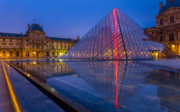 A stunning view of the Louvre at night, showcasing the illuminated glass pyramid reflecting in the surrounding water, highlighting the beauty of Parisian architecture.