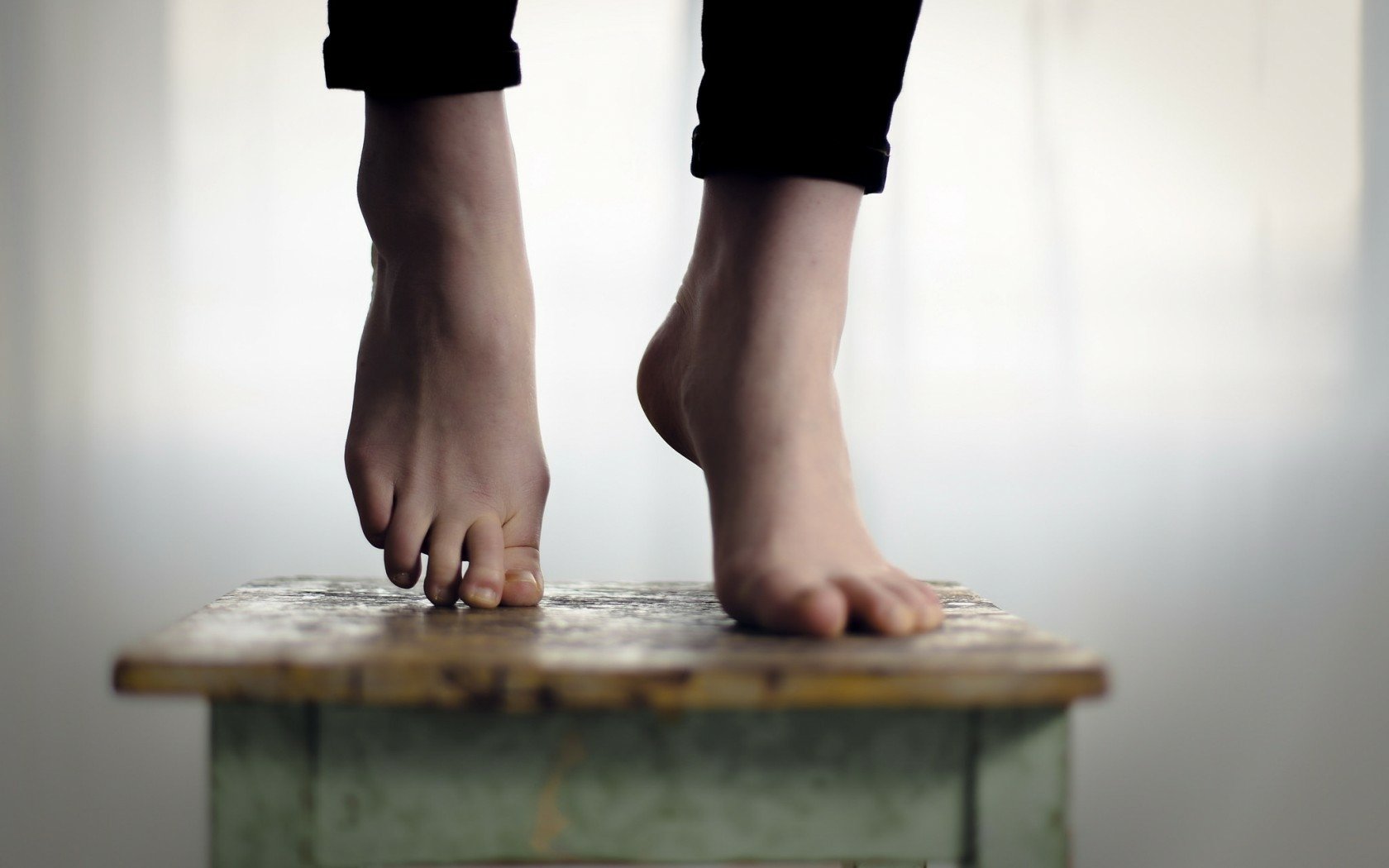 HD desktop wallpaper showing a close-up of a woman's feet with neatly manicured nails resting on a wooden surface.