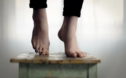 HD desktop wallpaper showing a close-up of a woman's feet with neatly manicured nails resting on a wooden surface.