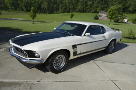 A white 1969 Ford Mustang Boss 302 muscle car parked on a driveway with a green landscape in the background, captured in high-definition for a PC desktop wallpaper.