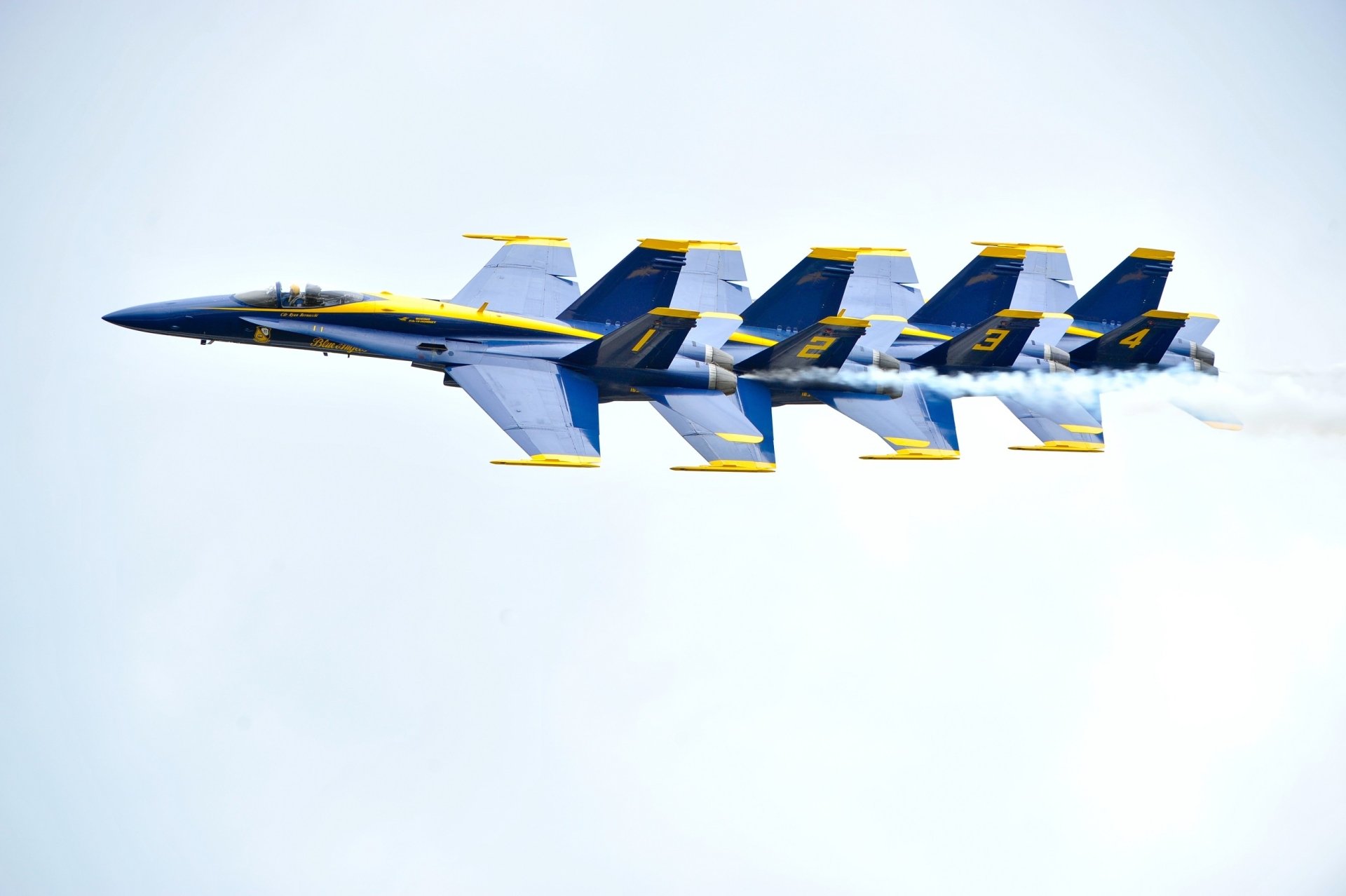 A formation of five McDonnell Douglas F/A-18 Hornet jet fighters from the Navy's Blue Angels performing an air show maneuver against a clear sky.