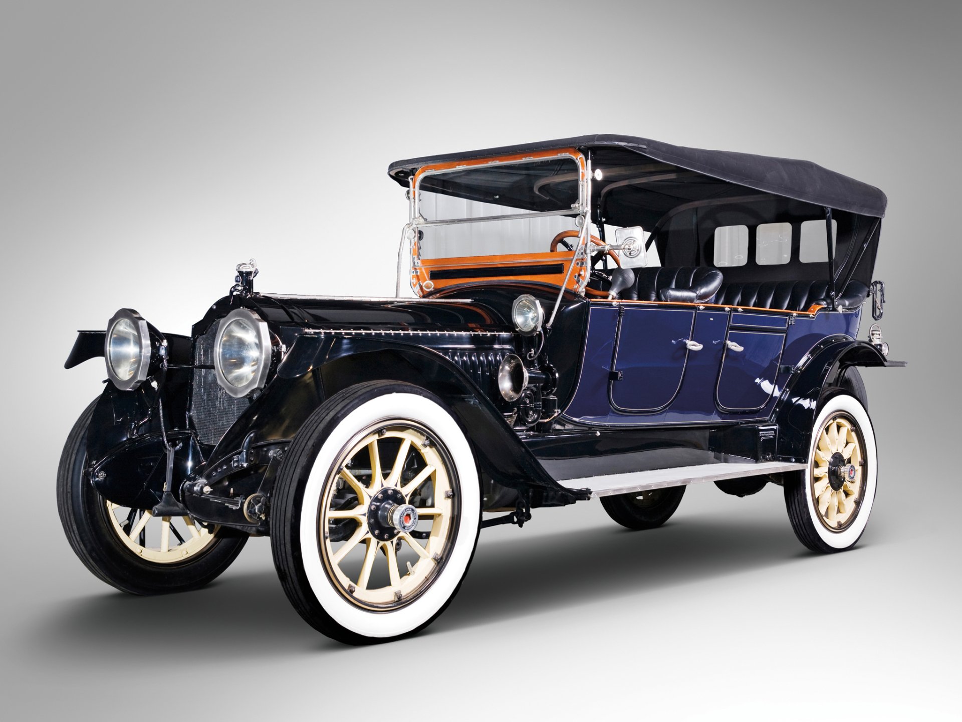 HD PC desktop background: vintage 1914 Packard Six Phaeton open touring vehicle, dark blue body, whitewall tires and black folding top.