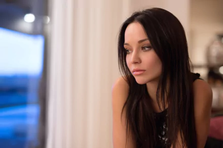 A brunette woman, modeled by Angelina Petrova, gazes thoughtfully out a window in this high-definition desktop wallpaper. Soft lighting enhances the intimate atmosphere.