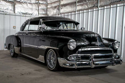 HD desktop wallpaper featuring a black 1951 Chevrolet DeLuxe lowrider parked inside a metallic warehouse.