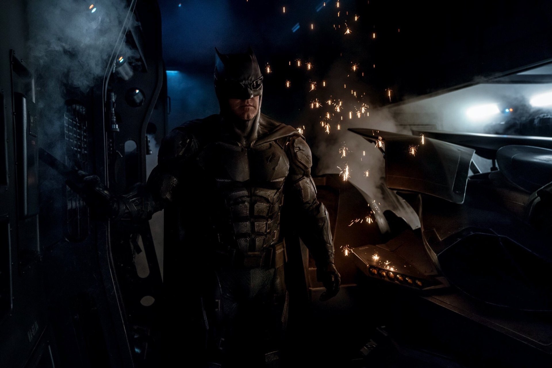A powerful HD wallpaper featuring Ben Affleck as Bruce Wayne, donning the Batman suit amidst sparks and dramatic lighting, capturing the essence of DC Comics' Justice League.
