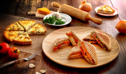 HD PC desktop wallpaper and background still life: grilled tomato sandwiches on a wooden platter beside a sliced quiche, garlic, parsley and a rolling pin on a rustic table.