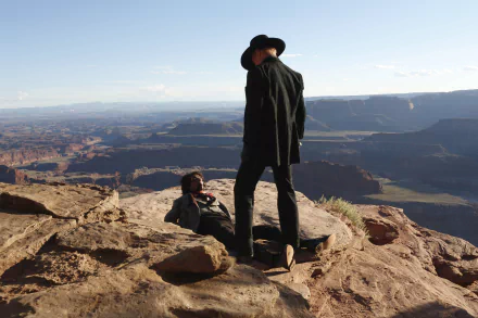 A dramatic scene from Westworld featuring Ed Harris standing over Eddie Rouse against a stunning canyon backdrop, highlighting the show's cinematic landscape. HD desktop wallpaper.