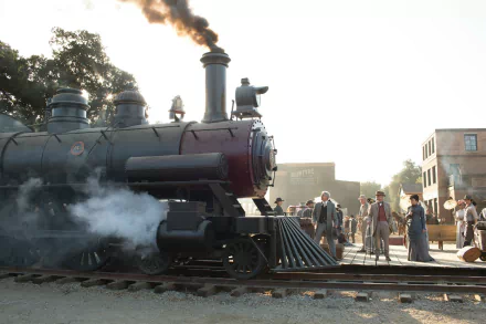 A vintage steam train stands on the tracks, surrounded by characters from the TV show Westworld, set against a sunlit backdrop, creating a captivating HD desktop wallpaper.