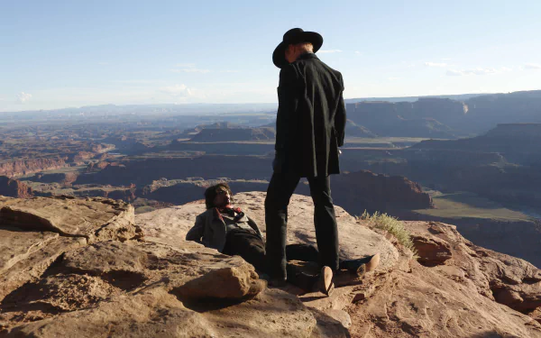 A dramatic scene from Westworld featuring Ed Harris standing over Eddie Rouse against a stunning canyon backdrop, highlighting the show's cinematic landscape. HD desktop wallpaper.