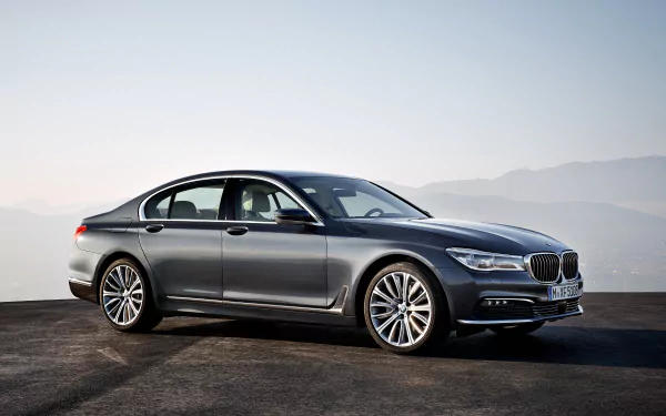 Silver BMW 7 Series sedan displayed on a scenic mountain backdrop in a crisp 4K Ultra HD desktop wallpaper.