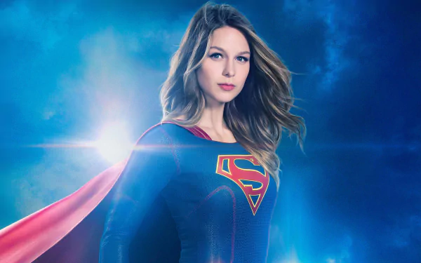 HD wallpaper featuring Melissa Benoist as Supergirl from the TV show Supergirl, standing confidently in her iconic costume with a blue and vibrant background.