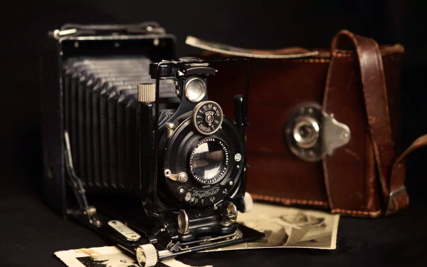 Vintage man-made camera with leather case and old photographs, captured in sharp 4K Ultra HD detail for PC desktop wallpaper and background.
