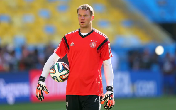 Manuel Neuer, the German goalkeeper, stands ready in a vibrant red jersey and gloves, captured in a dynamic HD sports wallpaper.