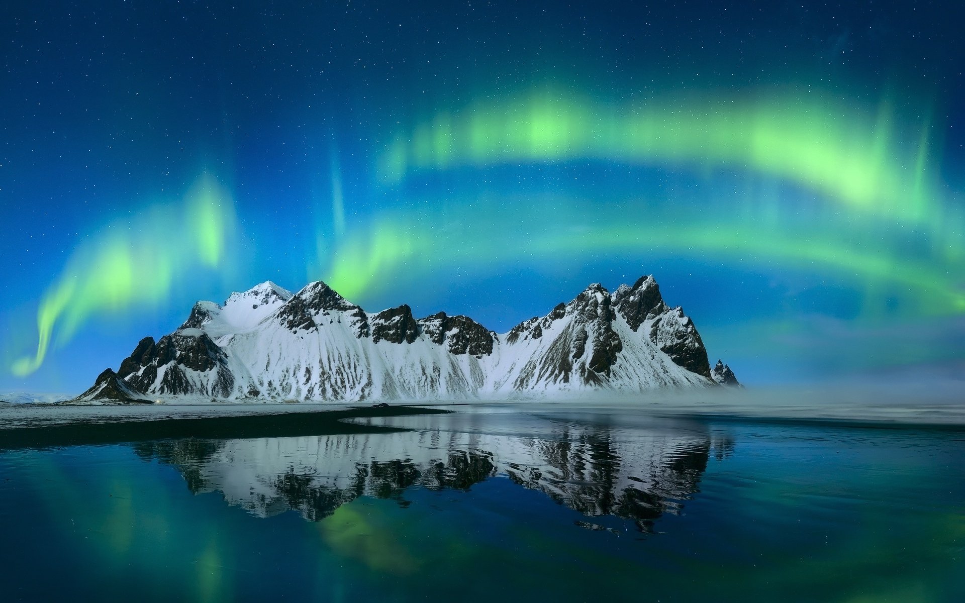 A breathtaking view of a starry sky illuminated by the aurora borealis, reflecting off a tranquil mountain lake, showcasing the beauty of nature in vibrant colors.