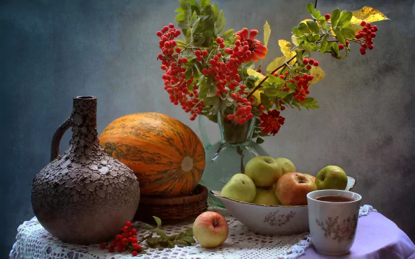 Still life HD desktop wallpaper featuring a ceramic pitcher, pumpkin, apples in a bowl, a cup of tea, and red berries arranged on a lace-covered table in a fall-themed setting.