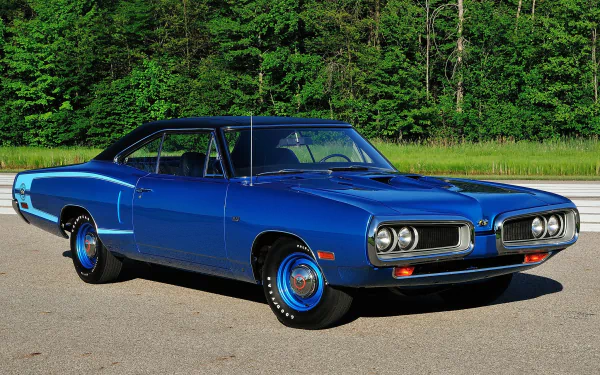 A vibrant blue Dodge Coronet Super Bee Hardtop Coupe parked on pavement with lush green trees in the background, shown in an HD PC desktop wallpaper style.
