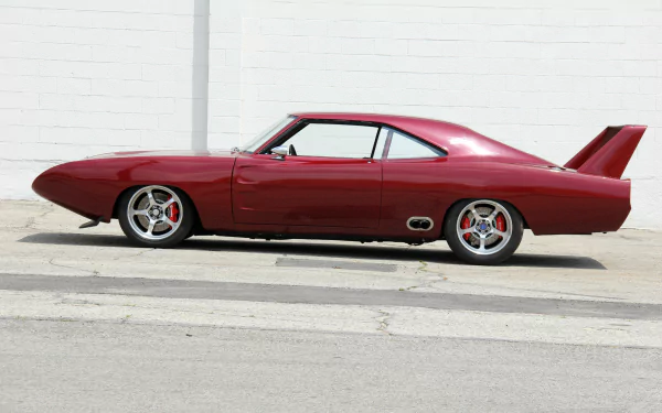 Red custom hot rod coupe with rear wing, side view, parked by a white brick wall. 2K Quad HD PC desktop wallpaper and background.