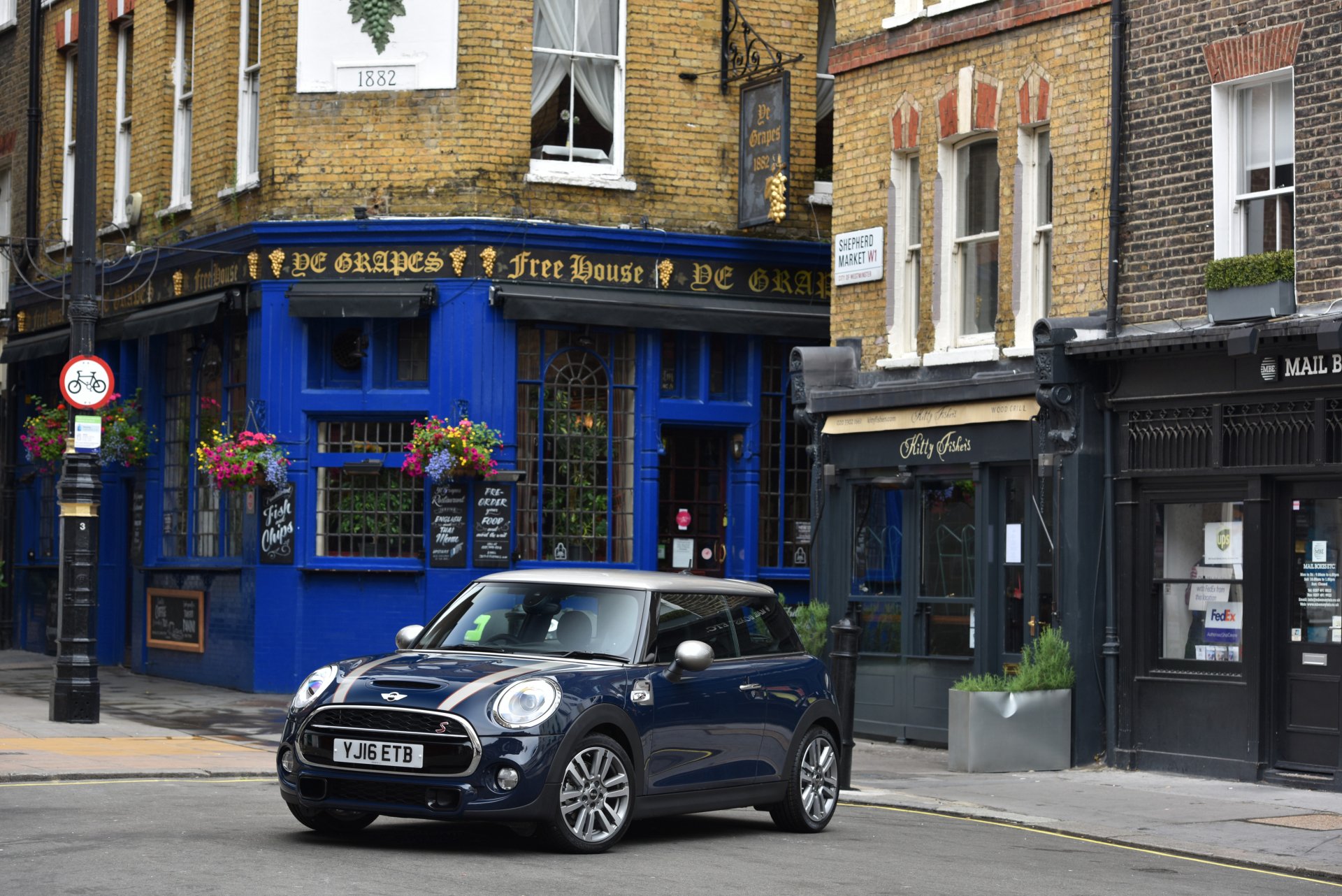 4K Ultra HD PC desktop wallpaper of a dark blue Mini Cooper compact car parked on a city street outside a blue pub — car, vehicle, Mini, Mini Cooper.