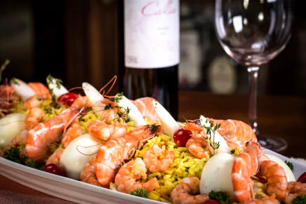 A vibrant seafood meal featuring shrimp served over yellow rice on a plate, with a wine bottle and glass in the background, captured in 4K Ultra HD quality.