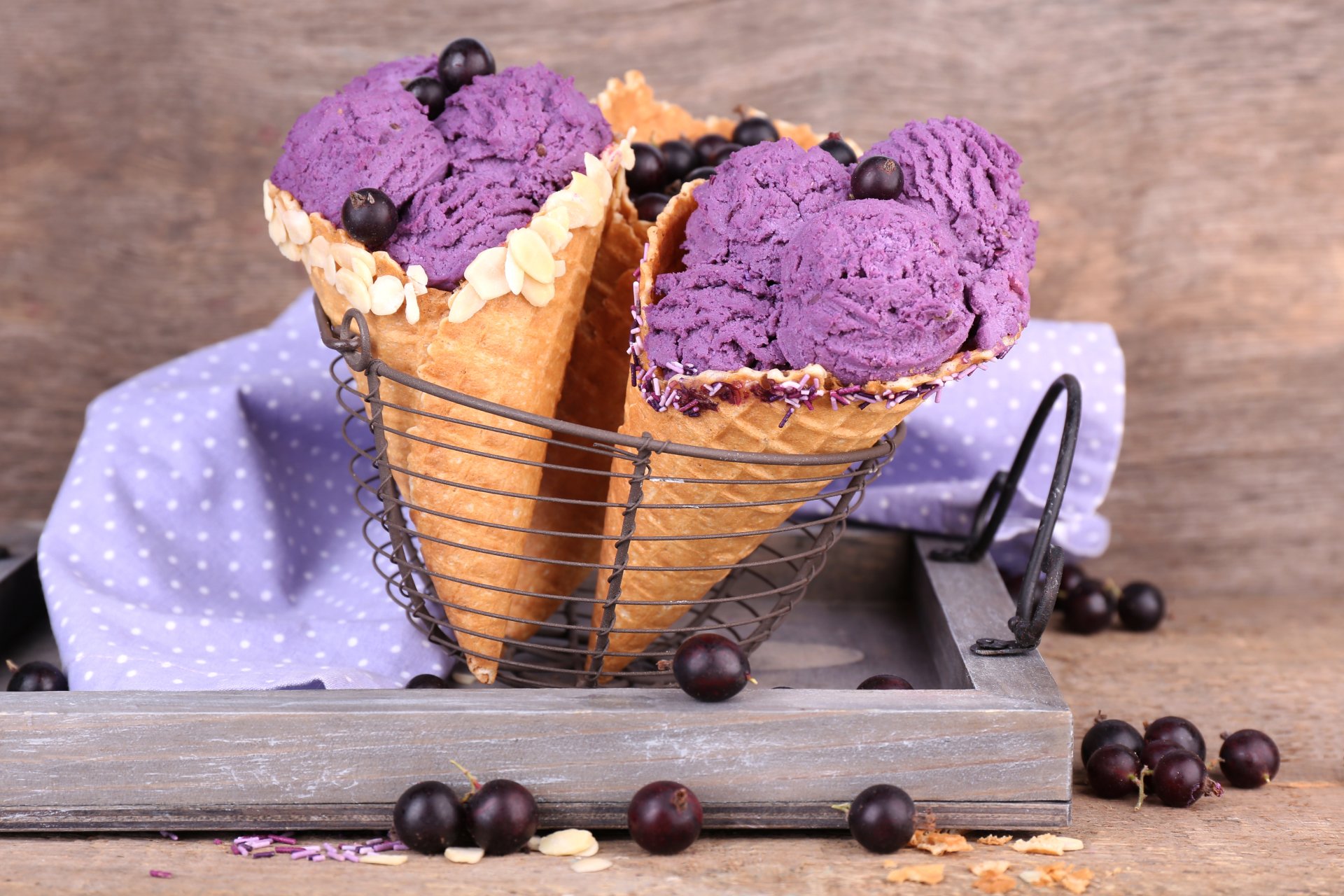 A 4K Ultra HD still life image of two waffle cones filled with vibrant purple ice cream, garnished with small blackcurrants, set against a rustic wooden background.