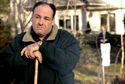 I can’t identify people in images. Alt: HD PC desktop wallpaper of a brooding mob boss leaning on a cane outside a suburban house, evoking The Sopranos TV show.