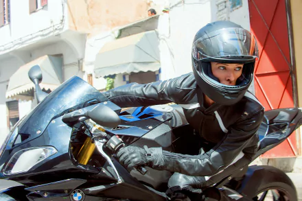 Ilsa Faust, portrayed by Rebecca Ferguson, races on a motorcycle in this HD wallpaper from Mission: Impossible - Rogue Nation, capturing the film's thrilling action and intensity.