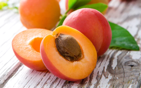 Vibrant close-up of ripe peaches, one halved showing the pit on weathered wood — fruit, food, peach image rendered as a 5K Ultra HD PC desktop wallpaper background.