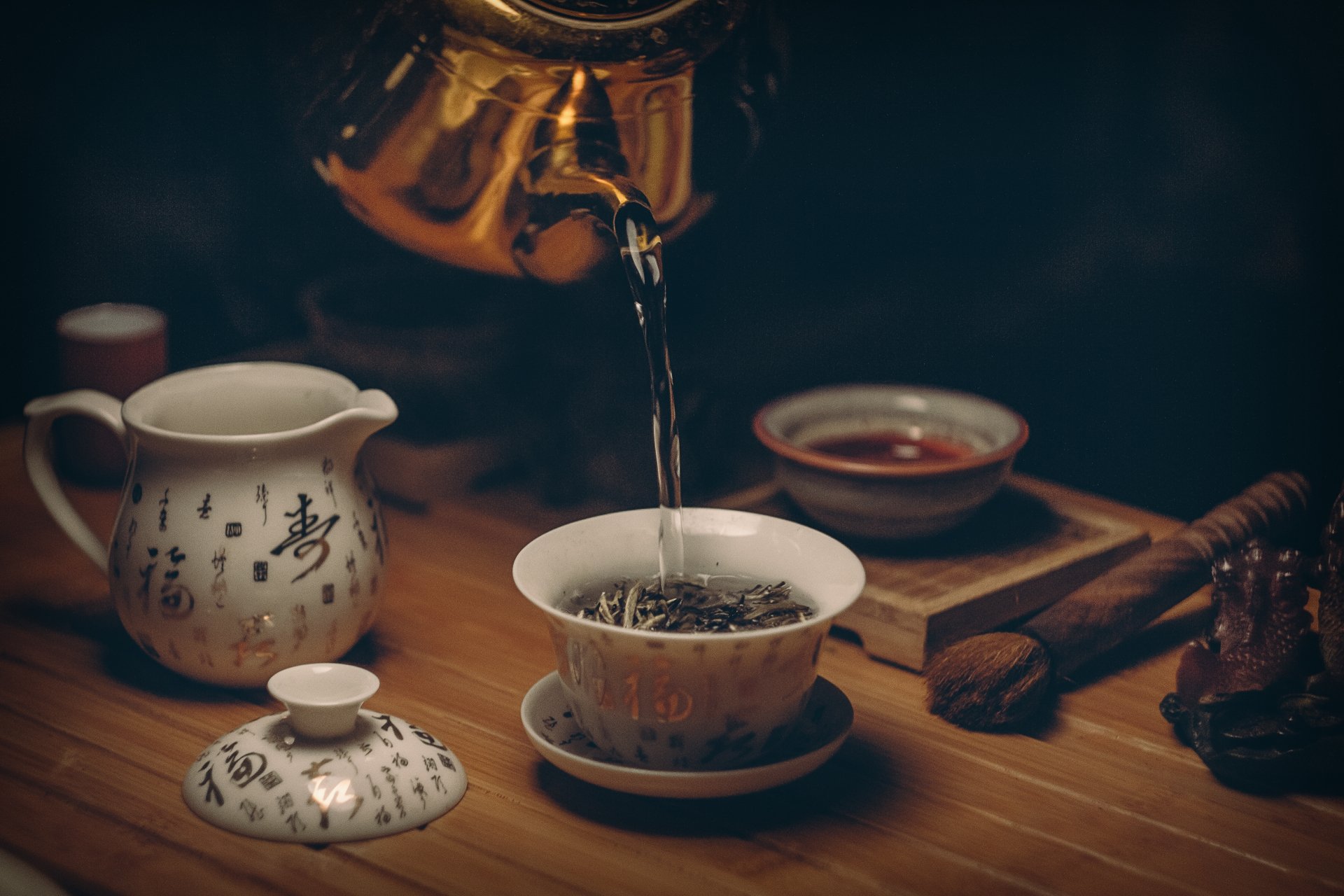 4K Ultra HD wallpaper showcasing a teapot pouring tea into a traditional cup, accompanied by a matching creamer on a wooden table, evoking a serene tea moment.